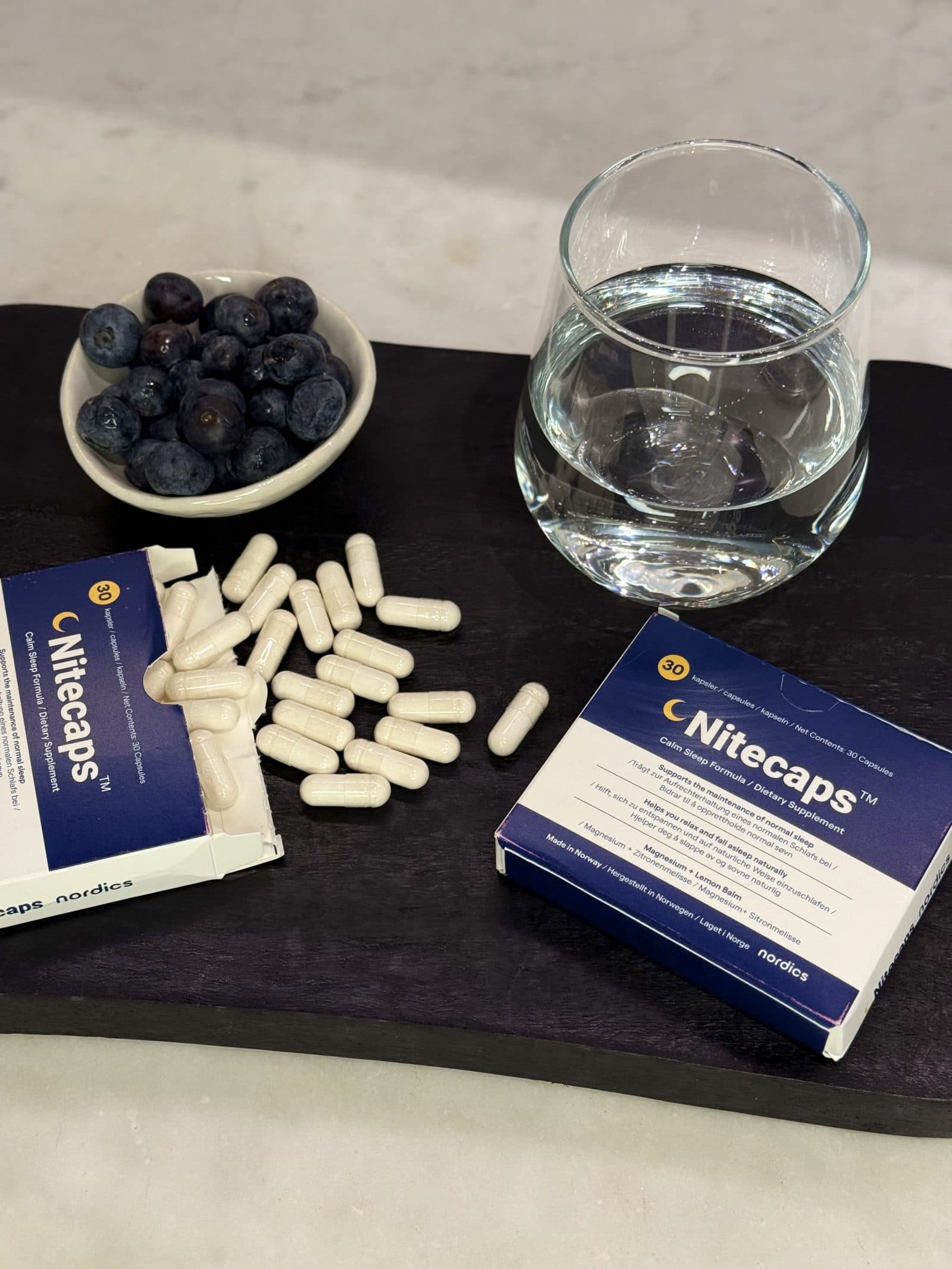 NiteCaps melatonin-free food supplement with capsules and a glass of water.